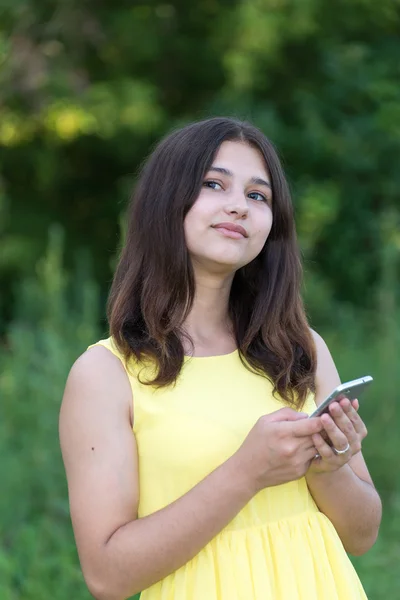14 років дівчина тримає мобільний телефон і дивиться вгору — стокове фото