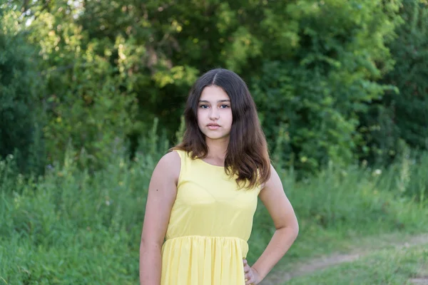 Teen girl in yellow dress standing in the park — Stock Photo, Image