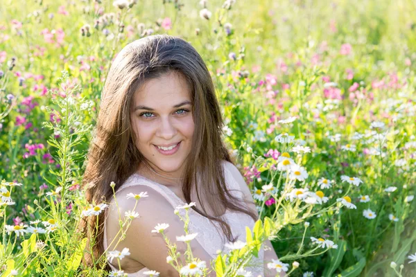 Belle fille aux cheveux longs sur clairière avec des fleurs de prairie — Photo