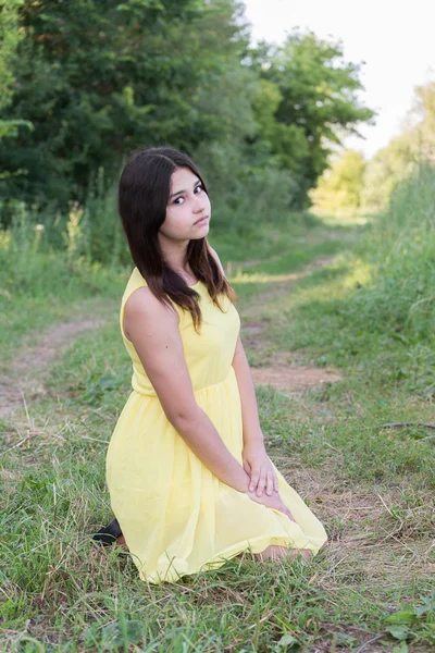 Das Mädchen im gelben Kleid sitzt auf dem Gras — Stockfoto