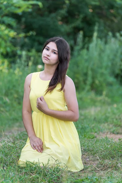 Das Mädchen im gelben Kleid sitzt auf dem Gras — Stockfoto