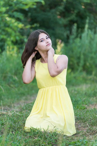 The girl in yellow dress sitting on grass — Stock Photo, Image