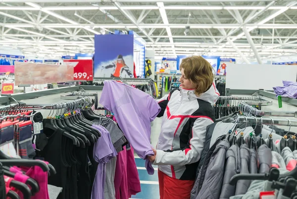 Mujer de mediana edad elige ropa en la tienda de deportes — Foto de Stock