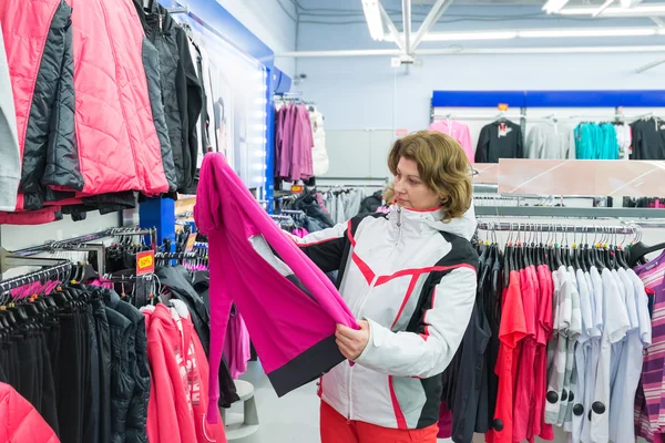 Mujer de mediana edad elige ropa en la tienda de deportes — Foto de Stock