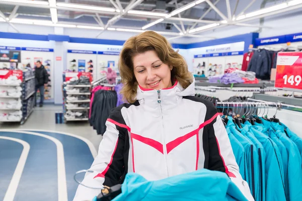 Mujer de mediana edad elige ropa en la tienda de deportes — Foto de Stock