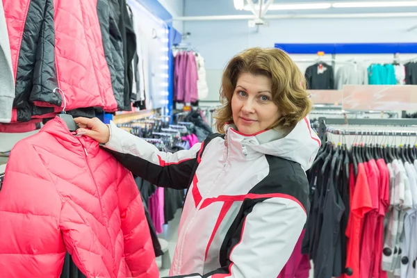 Mujer de mediana edad elige ropa en la tienda de deportes — Foto de Stock
