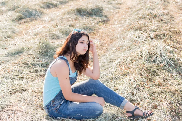 Nadenkend tiener meisje in een veld met str — Stockfoto