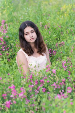 çayır çiçeklerle üzerinde oturan kız