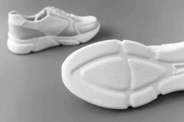 Δύο λευκά γυναικεία δερμάτινα αθλητικά παπούτσια σε γκρι φόντο — Φωτογραφία Αρχείου