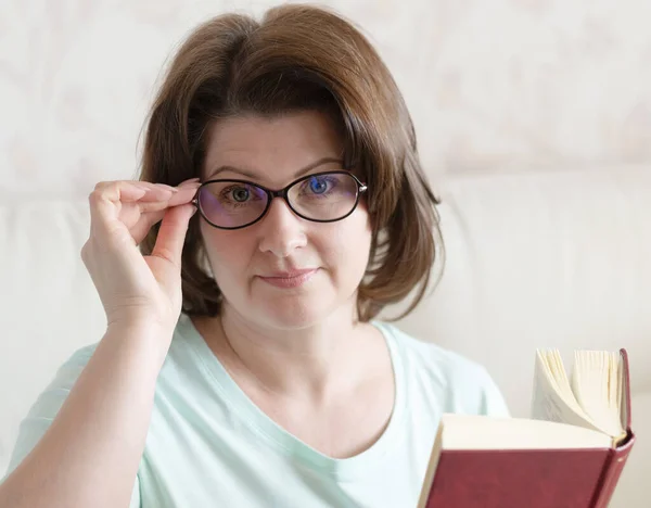 Wanita Berkacamata Dengan Buku Duduk Sofa — Stok Foto