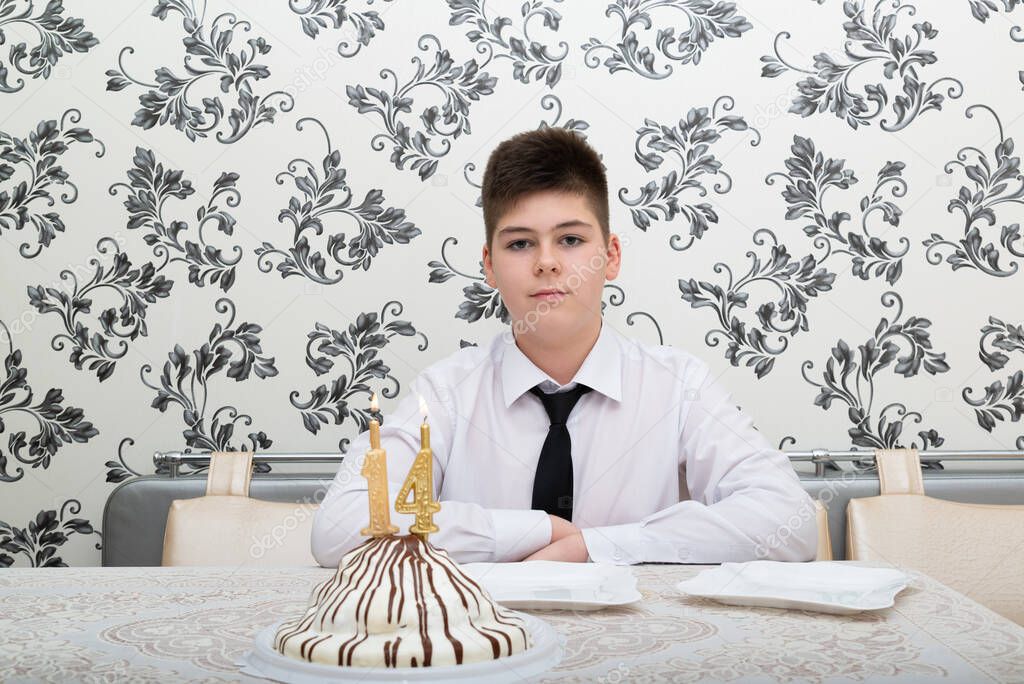 teen boy at the table with cake for his fourteenth birthday