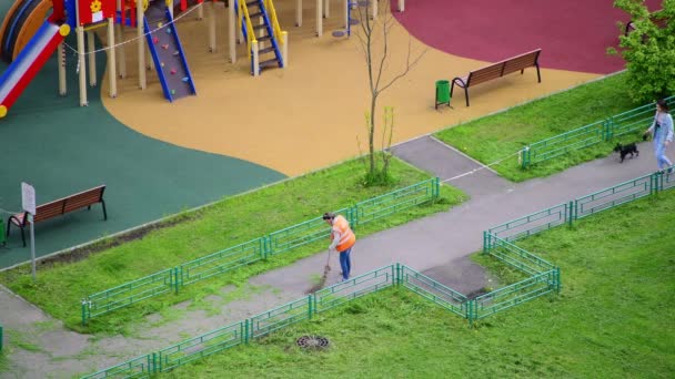 러시아 모스크바 - 7 월 15 . 2021 일. 관리인 이 잔디를 쓸고 있어. 도시 경관 — 비디오