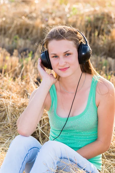 Fille écoute de la musique dans le champ — Photo