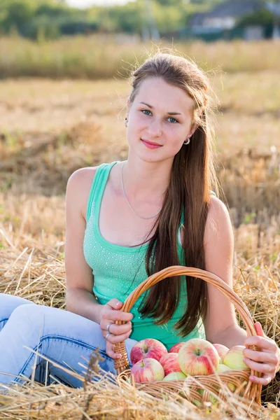 Teen girl with a basket of apples in  field — Stock Photo, Image