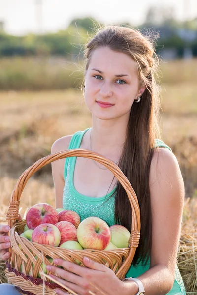 Teen girl with a basket of apples in  field — Stock Photo, Image