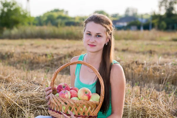 Teen girl with a basket of apples in  field — Stock Photo, Image
