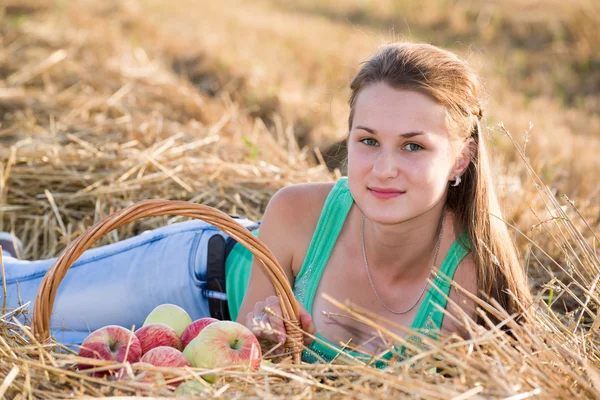 Teenie-Mädchen mit Korb voller Äpfel auf dem Feld — Stockfoto