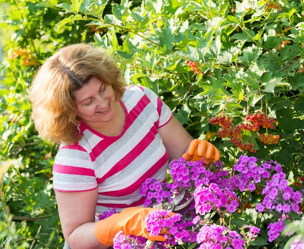Mujer bonita cuida detrás de las plantas en el jardín — Foto de Stock