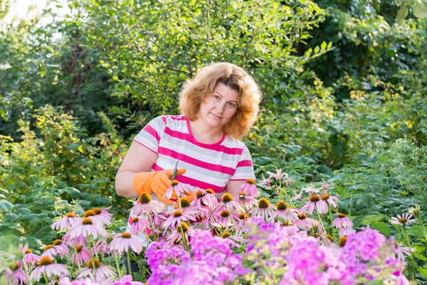 Jolie femme s'occupe derrière les plantes dans le jardin — Photo