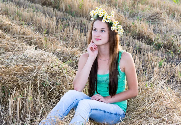 Chica con corona de margaritas en un campo — Foto de Stock