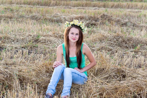 Chica con corona de margaritas en un campo — Foto de Stock