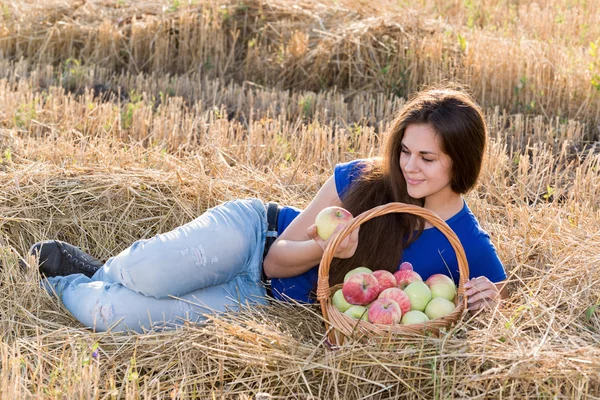 Дівчина-підліток з кошиком яблук у полі — стокове фото