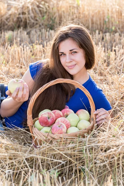 Teen girl with a basket of apples in  field — Stock Photo, Image