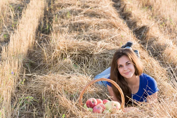 Menina adolescente com uma cesta de maçãs no campo — Fotografia de Stock