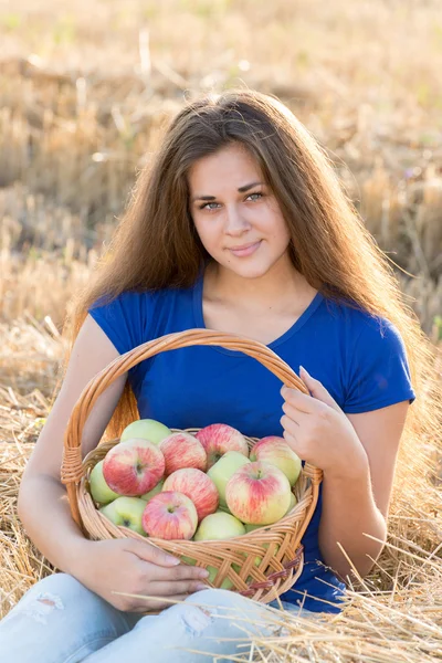 Teen girl with a basket of apples in  field — Stock Photo, Image