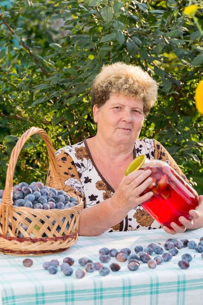 Wanita tua dengan stoples plum compote — Stok Foto