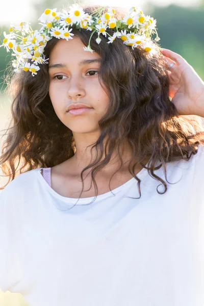 Tiener meisje met een krans van madeliefjes in veld — Stockfoto
