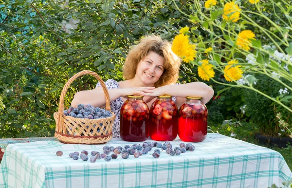 Žena s kompot švestky v zahradě — Stock fotografie