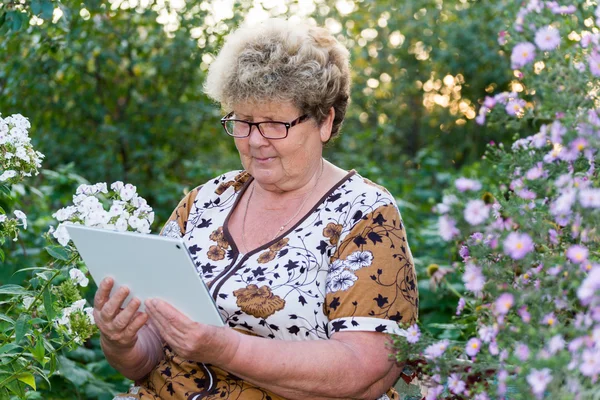 Mujer mayor usando tableta digital en el jardín del hogar — Foto de Stock