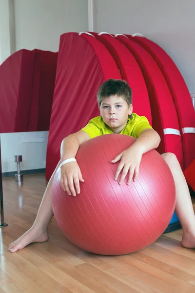 Boy does exercise with the ball in gym — Stock Photo, Image