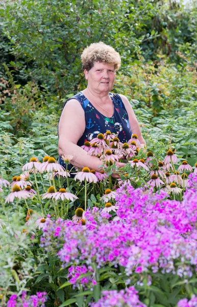 Zralá žena s květinami v garden — Stock fotografie