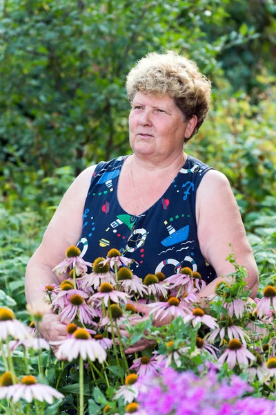 Ώριμη γυναίκα με λουλούδια στον κήπο — Φωτογραφία Αρχείου