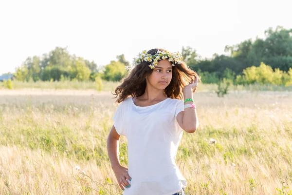 Teenie-Mädchen mit einem Kranz aus Gänseblümchen im Feld — Stockfoto