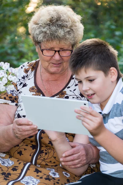 Бабушка с внуком смотрят планшетный компьютер — стоковое фото