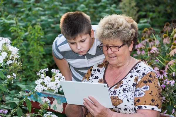Mormor med barnbarn tittar på TabletPC — Stockfoto