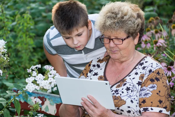 Mormor med barnbarn tittar på TabletPC — Stockfoto