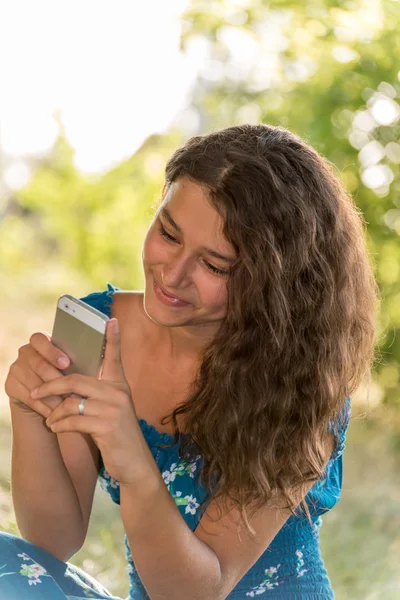 Menina adolescente com um telefone no parque — Fotografia de Stock