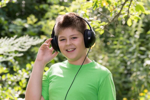 Boy poslouchal hudbu se sluchátky v parku — Stock fotografie