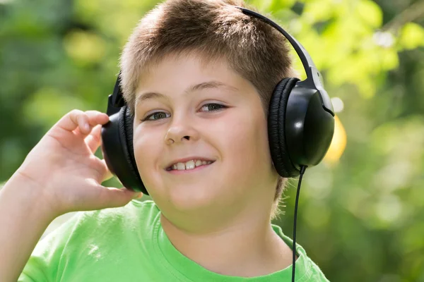 Pojke lyssna på musik med hörlurar i park — Stockfoto