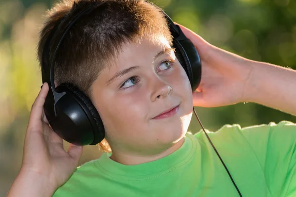 Chłopiec słuchanie muzyki w słuchawkach w parku — Zdjęcie stockowe
