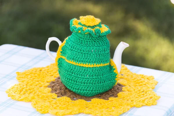 Gebreide kleedje op de theepot op natuurlijke achtergrond. — Stockfoto