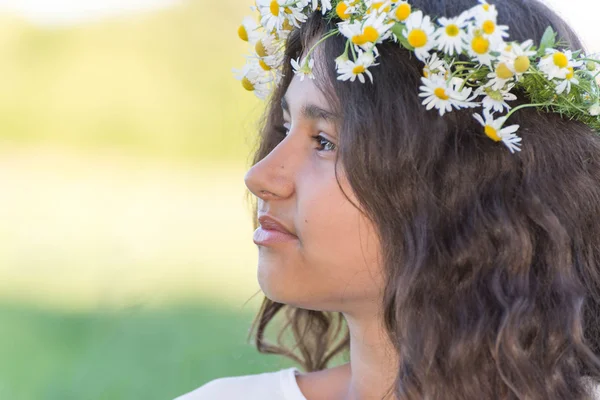 Tiener meisje met een krans van margrieten op de aard — Stockfoto