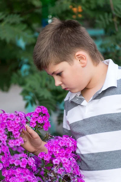 Menino adolescente sobre flores no jardim — Fotografia de Stock