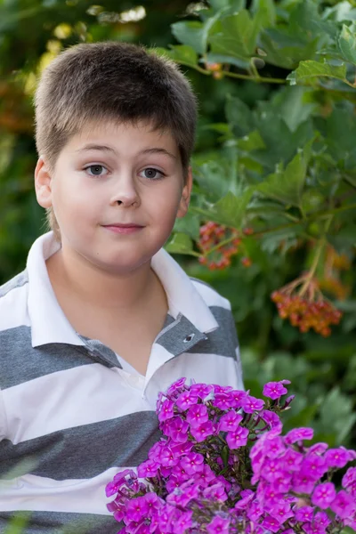 Ragazzo adolescente sui fiori in giardino — Foto Stock