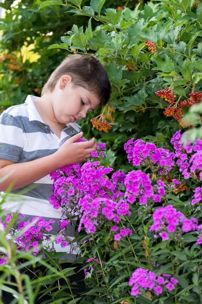 Menino adolescente sobre flores no jardim — Fotografia de Stock