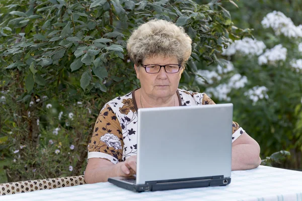 Bahçedeki bilgisayarda çalışan yaşlı kadın — Stok fotoğraf